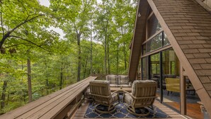 Une terrasse dotée de mobilier d’extérieur, offrant une vue sur une forêt.