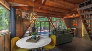 A wooden interior with a dining area, sofa, and staircase. - The Cocoon Chalet by Innsbrook Vacations! (Innsbrook)