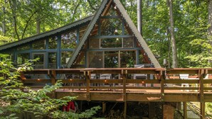 A cabin with a wooden deck and large windows, surrounded by trees. - The Cocoon Chalet by Innsbrook Vacations! (Innsbrook)
