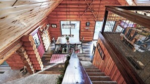 A cabin interior with a dining area, staircase, and a view of the outside. - Family Log Cabin - Lake, Golf, Pool, Hike, Ski-ATV & Game Room - Northwoods WI (Danbury)