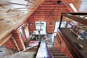 A cabin interior with a dining area, staircase, and a view of the outside. - Family Log Cabin - Lake, Golf, Pool, Hike, Ski-ATV & Game Room - Northwoods WI (Danbury)