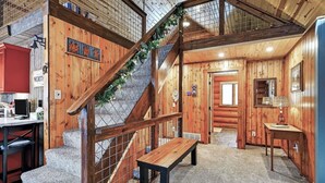 A wooden interior with a staircase, a bench, and a kitchen area. - Family Log Cabin - Lake, Golf, Pool, Hike, Ski-ATV & Game Room - Northwoods WI (Danbury)