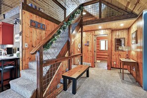 A wooden interior with a staircase, a bench, and a kitchen area. - Family Log Cabin - Lake, Golf, Pool, Hike, Ski-ATV & Game Room - Northwoods WI (Danbury)