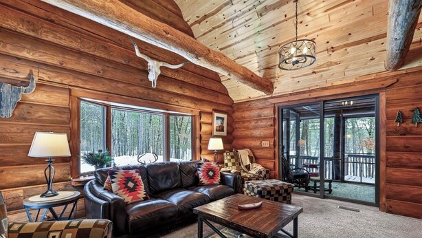 A log cabin interior with a leather sofa, coffee table, and patterned armchairs. - Family Log Cabin - Lake, Golf, Pool, Hike, Ski-ATV & Game Room - Northwoods WI (Danbury)