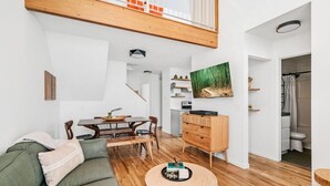 Una sala de estar moderna con una mesa de comedor de madera, un sofá verde y una mesa de centro redonda de madera.