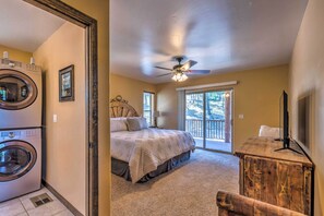 A bedroom with a bed, a ceiling fan, a wooden dresser, and a washing machine. - Quiet Ruidoso Cabin w/ Deck & Private Hot Tub (Ruidoso)