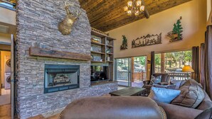 Una sala de estar acogedora con chimenea de piedra, muebles de cuero y un ventanal con vistas a una terraza.
