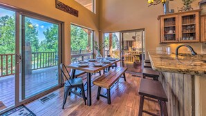 Una cocina amplia con una mesa y banco de madera, ventanas grandes y vistas al exterior.