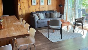 En inredning med träpanel, ett matområde, en soffa och en takfläkt.