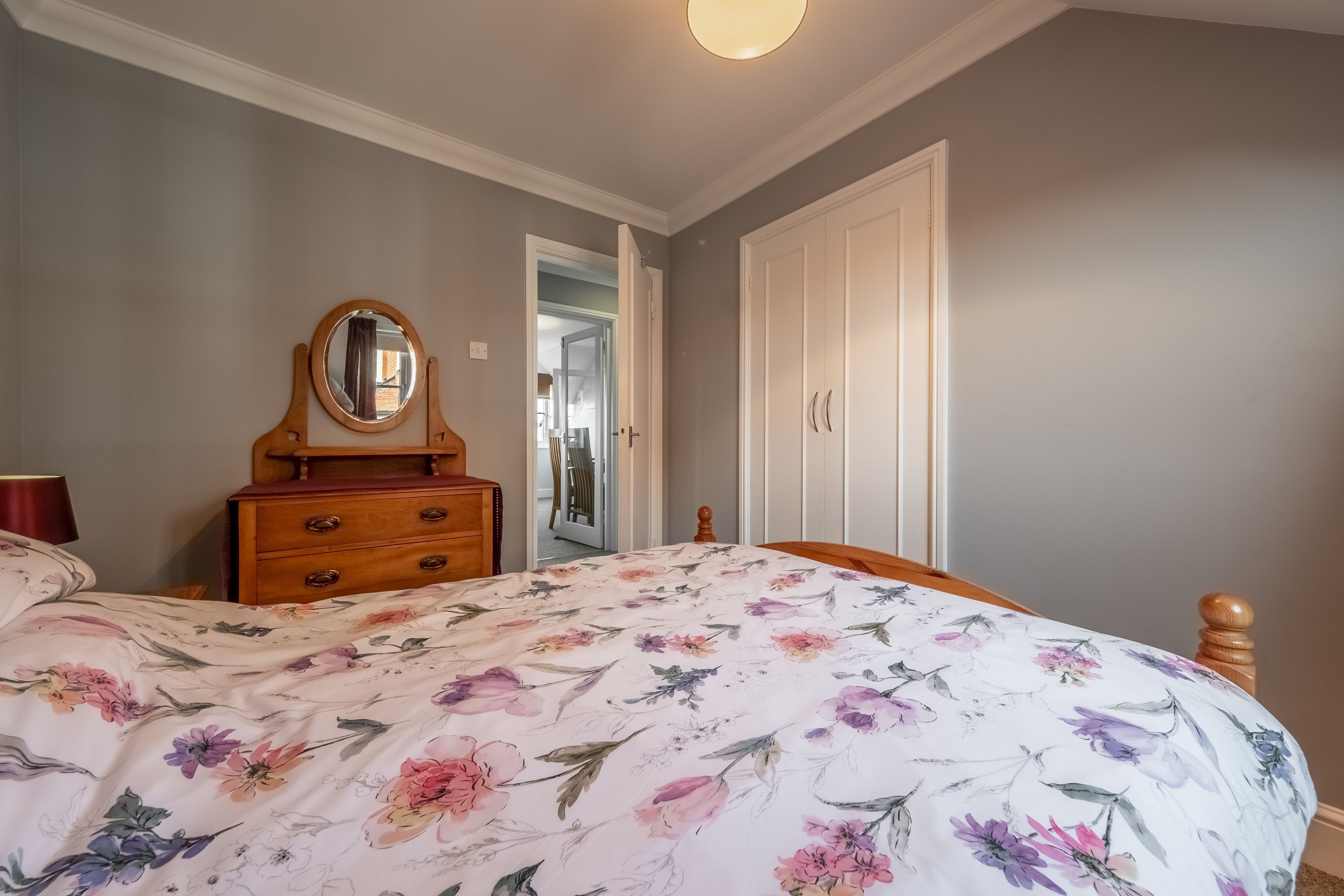 A bedroom with a bed, dresser, mirror, and wardrobe.