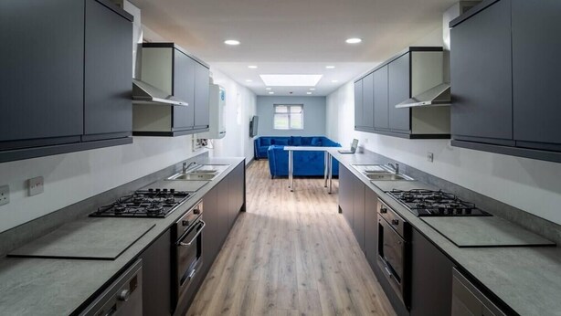 Een moderne keuken met twee gaspitten, een centraal kookeiland, en een blauwe bank op de achtergrond.
