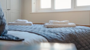 Una cama bien hecha con toallas blancas dobladas y una ventana con luz natural.