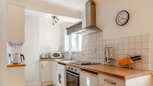 Una cocina moderna con armarios blancos, horno empotrado, microondas y lavavajillas.