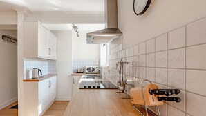 Una cocina moderna con armarios blancos, una campana extractora de acero inoxidable, un microondas y una tabla de cortar de madera con cuchillos.