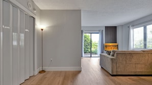 A modern living room with a sofa, a floor lamp, and a view of the outdoors through a glass door. - Excellent Resort Studio near Universal & Disney (Orlando)