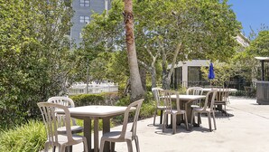 Outdoor patio seating with tables and chairs, surrounded by greenery and a building in the background. - Excellent Resort Studio near Universal & Disney (Orlando)