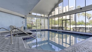 An indoor swimming pool with clear glass walls, a tiled floor, and a hot tub area. - Excellent Resort Studio near Universal & Disney (Orlando)