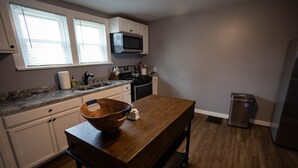 A kitchen with white cabinets, a wooden table, a microwave, and a refrigerator.