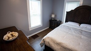 A bedroom with a bed, a nightstand, a lamp, and a window.