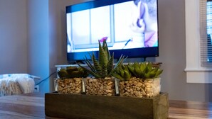 A living room with a wooden coffee table, a television, and a plant arrangement on the coffee table.