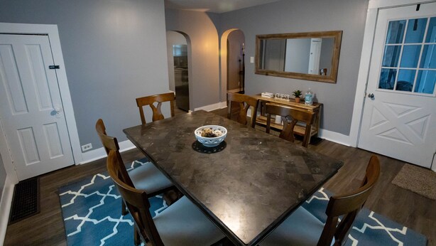 A dining room with a rectangular table, six chairs, a bowl of fruit, and a wooden sideboard.