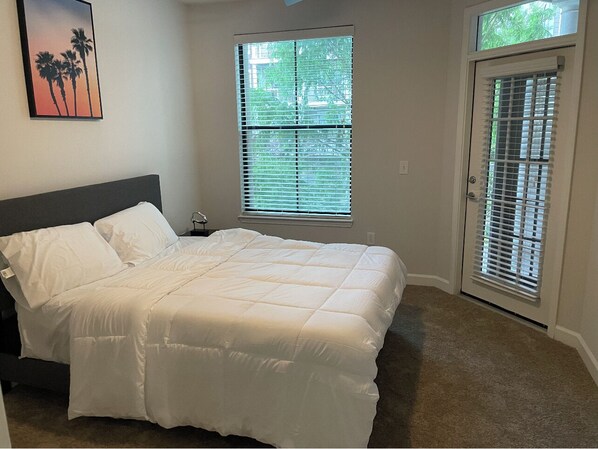 Relax in this serene bedroom with a large bed, framed picture, and natural light pouring in through the windows.