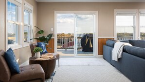 Un balcon spacieux offrant une vue sur un quai et des bateaux, aménagé avec un canapé, un fauteuil et une petite table agrémentée d’une plante.