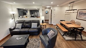 A modern living room with a leather sofa, a coffee table, and a dining area with a wooden table and chairs.