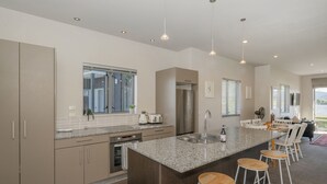 Een moderne keuken met granieten aanrechtbladen, roestvrijstalen apparatuur en een centraal eiland met barkrukken.