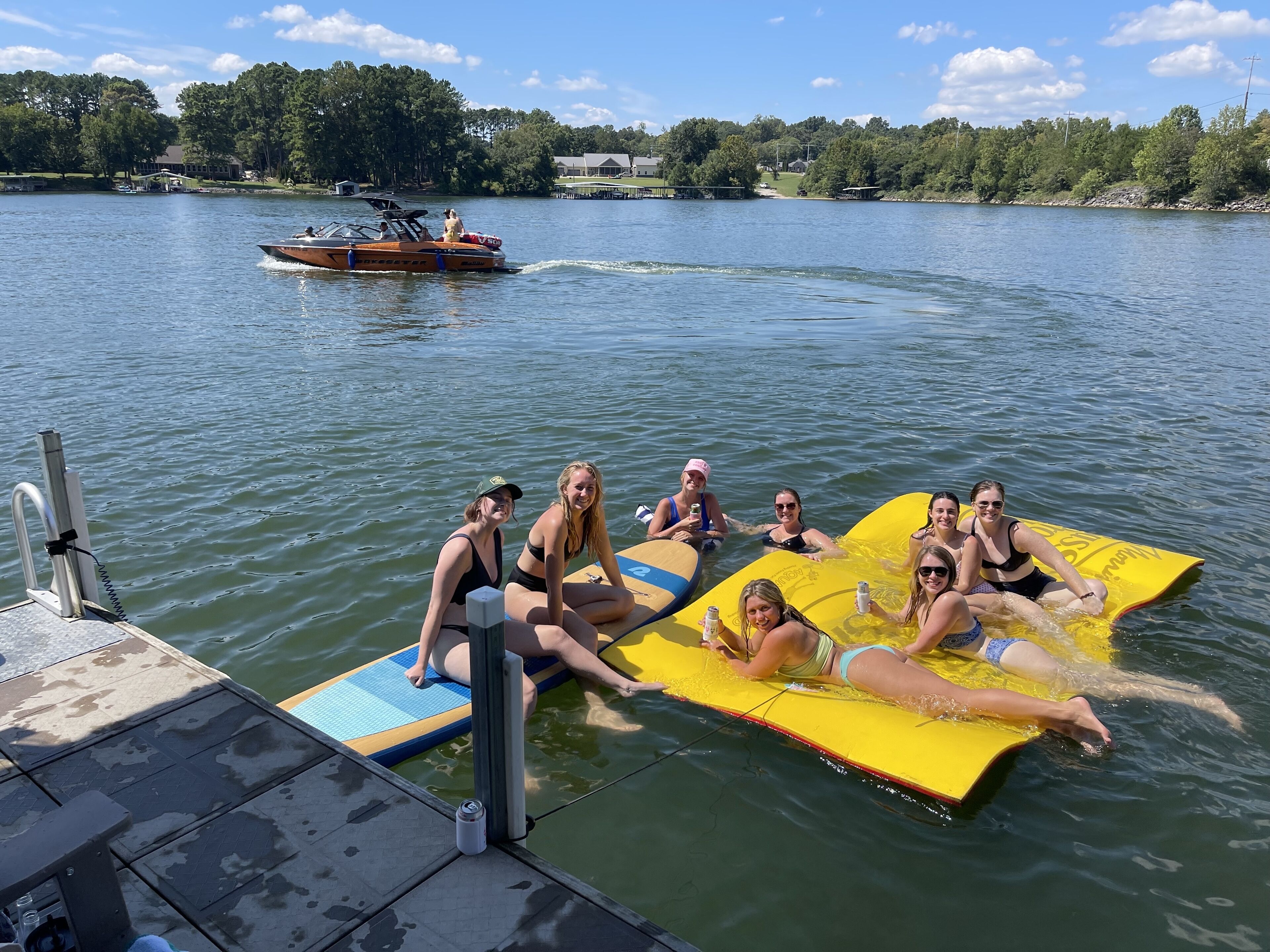Un groupe de personnes se trouve sur un bateau, avec une planche de wakeboard et une autre planche qui flotte sur l'eau.