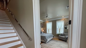 Quarto com cama, cadeira, escrivaninha e ventilador de teto.