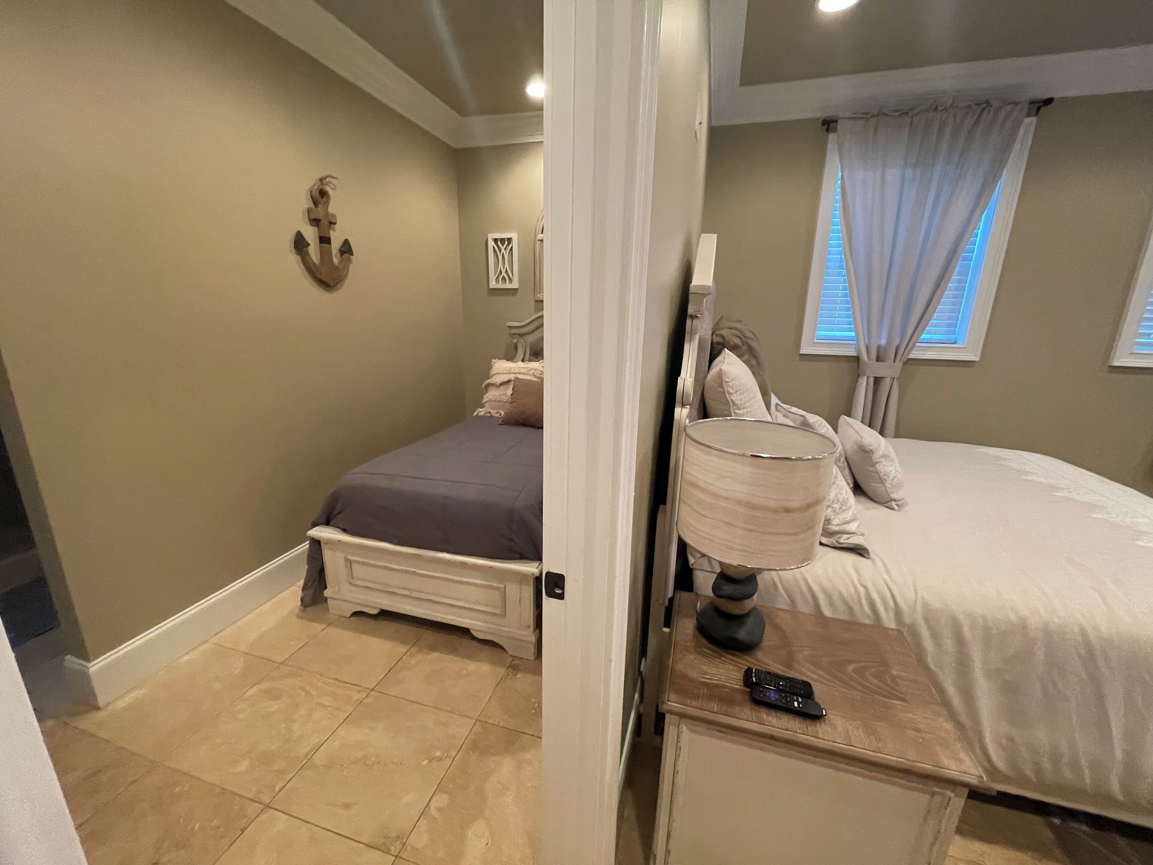 A bedroom with a bed, a nightstand, a lamp, and a remote control.