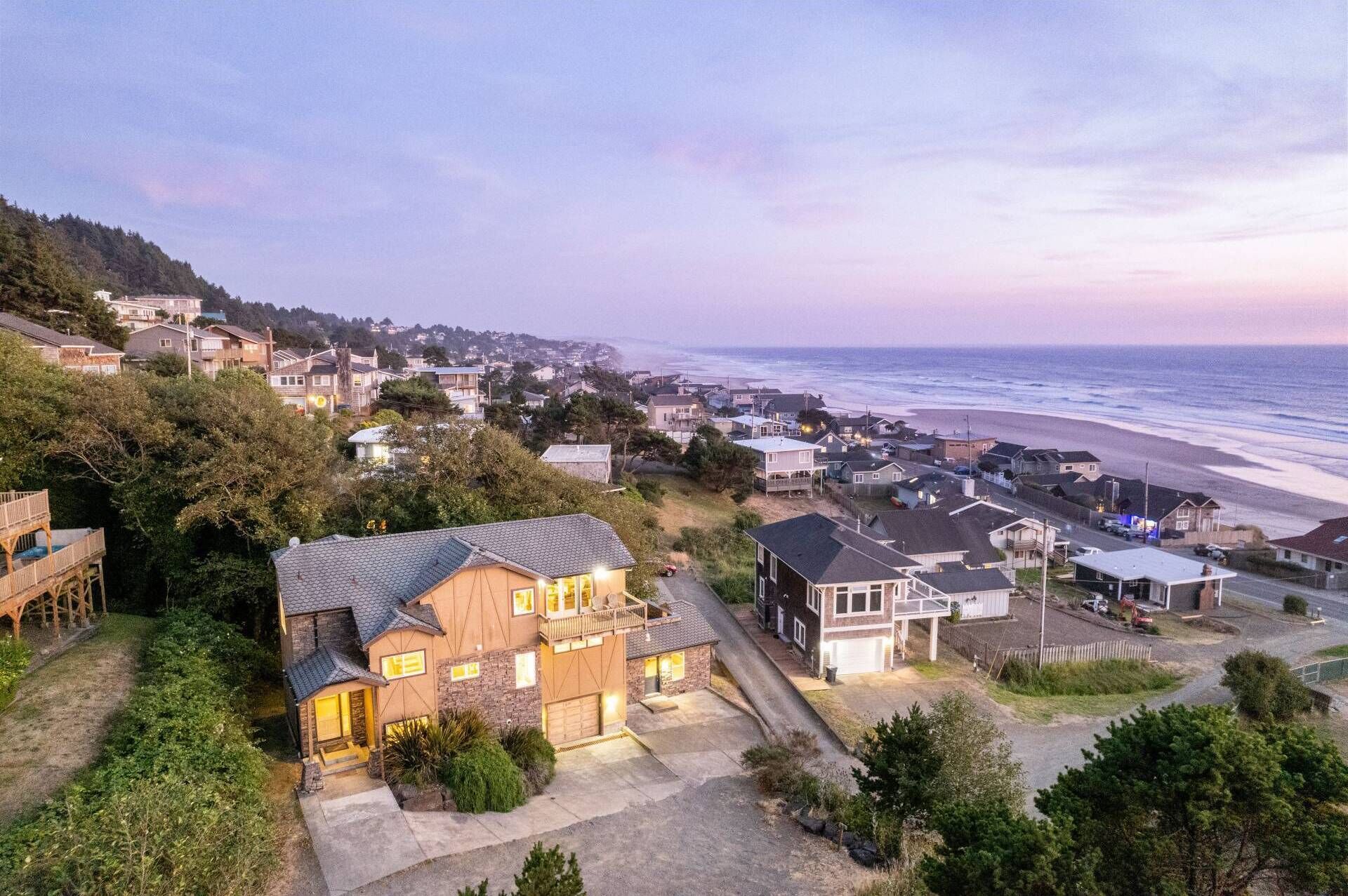 A coastal residential area with houses, a beach, and a large house with a balcony overlooking the ocean.