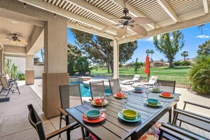 An outdoor patio with a pool, lounge chairs, and a table set for dining. - Golf Course Home w/ Private Pool, Spa, Casita, Firepit & Covered Patio Dining (Palm Desert)