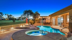 Ein Schwimmbecken mit Whirlpool, Liegestühlen und einer überdachten Terrasse.