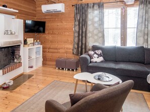 A cozy living room with a fireplace, a television, a sofa, and a small table. - Piilola nr 1 by Interhome (Kuusamo)