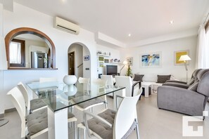Ein modernes Wohnzimmer mit einem Glastisch, weißen Sofas und einem grauen Sofa.