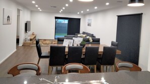 Ein moderner Essbereich mit einem rechteckigen Tisch, schwarzen Stühlen und Pendelleuchten.