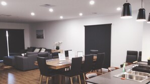 Eine moderne Küche mit einer zentralen Kochinsel, ein Essbereich mit Tisch und Stühlen sowie ein Wohnbereich mit Sofa und Couchtisch.