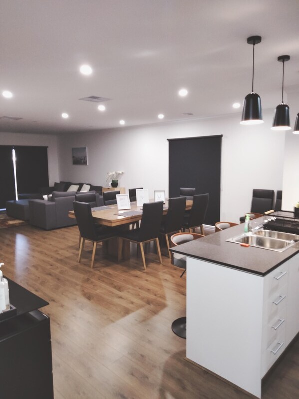 A modern kitchen with a central island, a dining area with a table and chairs, and a living area with a sofa and a coffee table.