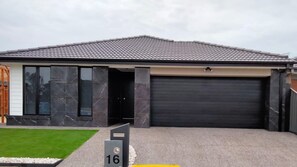 Een modern herenhuis met een donkergrijze pannendak, een zwarte garagepoort en een verzorgd gazon.