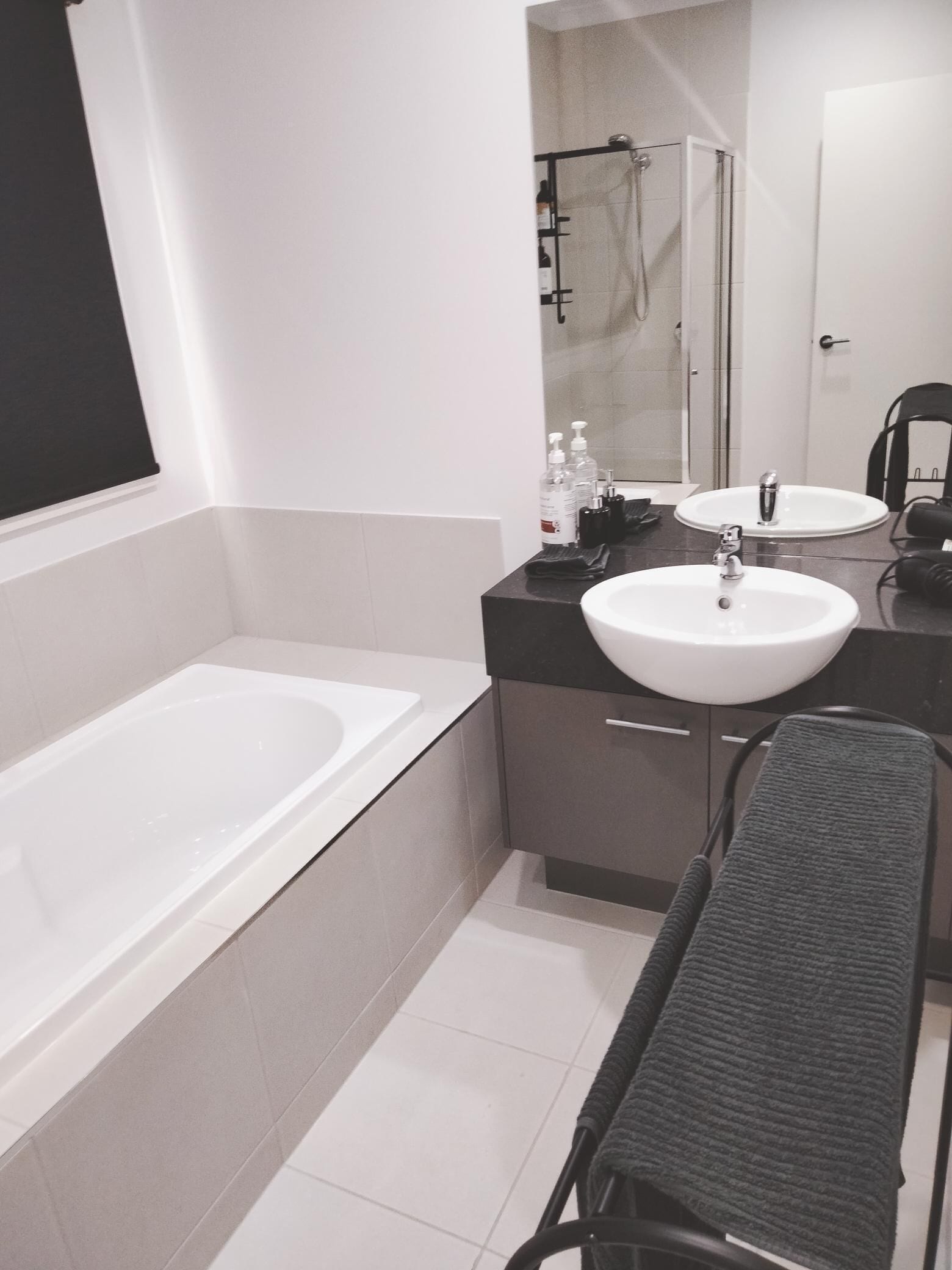 A modern bathroom with a bathtub, two sinks, a shower, and a bench.
