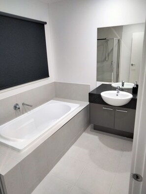Een moderne badkamer met een ruime badkuip, een wastafel en een spiegel.