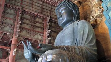 Una estatua grande de Buda en un templo con arquitectura de madera tradicional y ornamentos dorados intrincados.