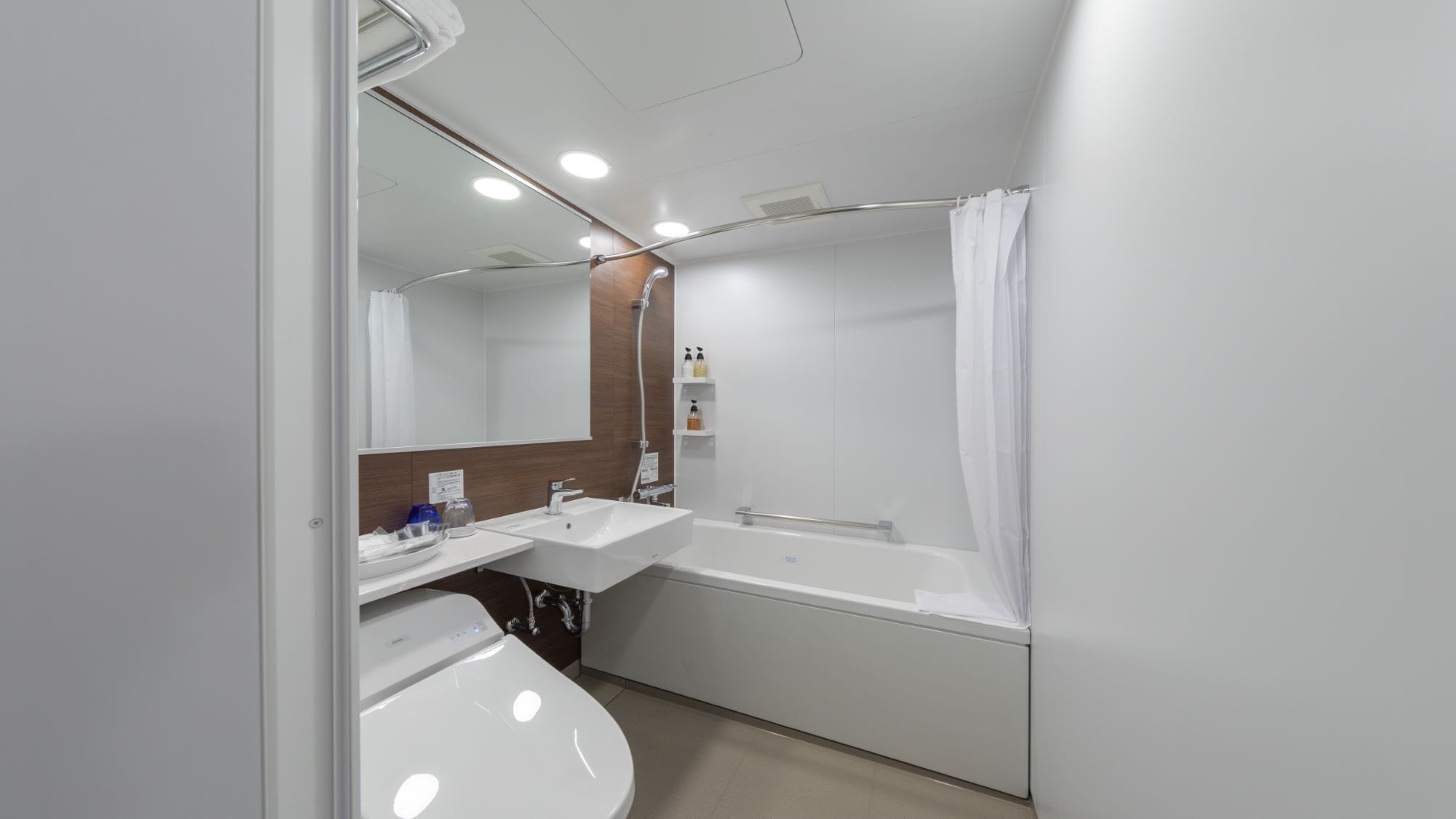 A modern bathroom with a white sink, a mirror, a bathtub, and a shower curtain.