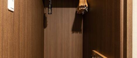 A compact bathroom with wooden walls, a bench, a towel rack, and a shower area.