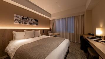 A modern hotel room with a large bed, a desk, and a chair.