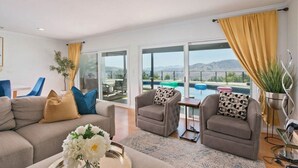 A modern living room with a sofa, armchairs, and a coffee table. There are large windows offering a view of the outdoors. - calabasas Home With stunning Views, Pool, and Jacuzzi  (Calabasas)