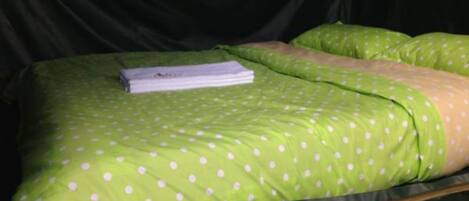 A bed with green bedding and a white pillow.