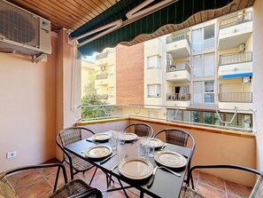 A balcony with a table set for four, overlooking a residential building with multiple balconies.